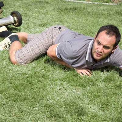 fallen man on lawn next to lawnmower