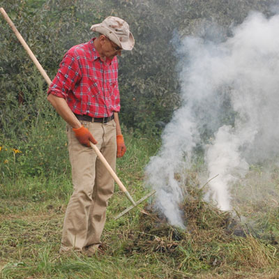 man holding rake and standing on lawn on fire