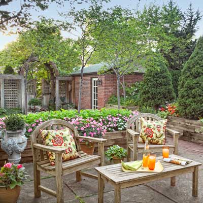 back yard lounge area conical dwarf Alberta spruces, serviceberry trees, coleus, impatiens, vining mandevilla