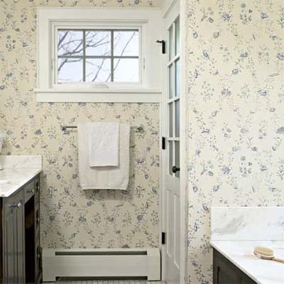paneled door hiding the bathroom in this remodeled shingle-style cottage