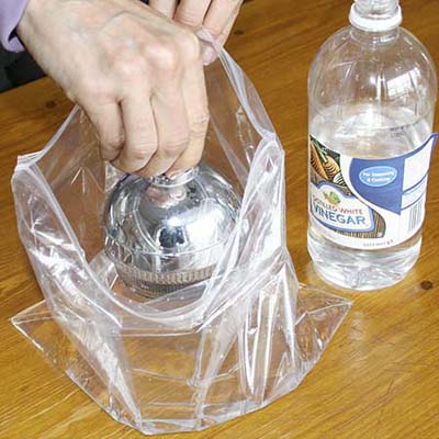 dipping a shower head into a plastic bag filled with vinegar