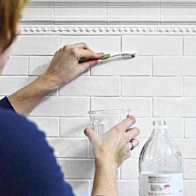 scrupping grout with toothbrush dipped in vinegar