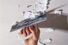hand smoothing new plaster over repaired areas of a ceiling