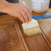 John Thomas paints a thick coat of commercial stripper on wood