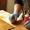 John Thomas rubs the stripped wood with fine steel wool and denatured alcohol