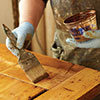 John Thomas brushes on very thin coats of a water-based glaze