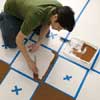 starting to paint the dark squares in a checkerboard pattern on a wood floor
