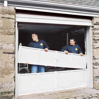 two workers dismantling a common overhead garage door