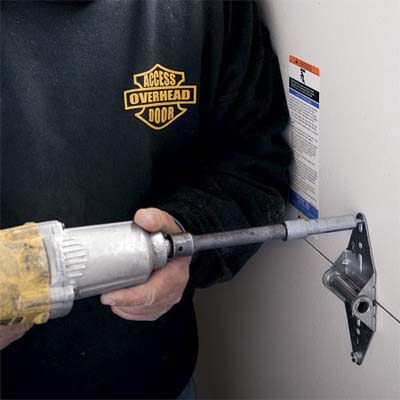 driver screwing the hinges in place to hold together two garage door sections
