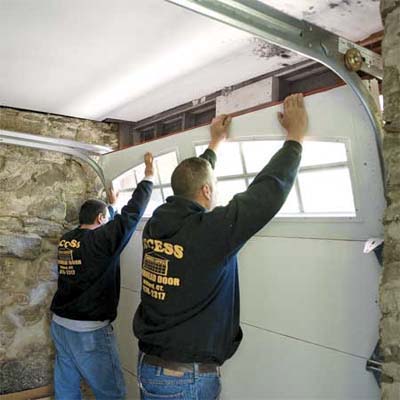 two workers lifting the last door section into place
