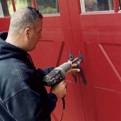worker attaching the hardware to the outside of the new carriage-style doors