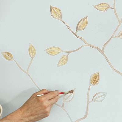 gold paint applied to leaves sketched on a wall