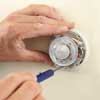 person unscrewing an old thermostat in order to remove it