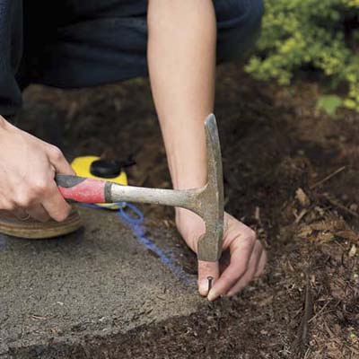 person puts nails in concrete driveway next to chalk line