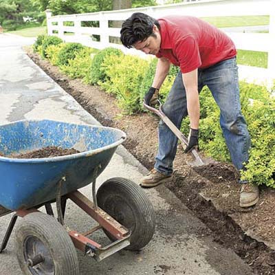 Mark Powers digs a trench next to an asphalt driveway