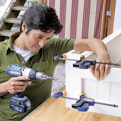 person using clamps and a drill to hold together the sides of this all weather planter