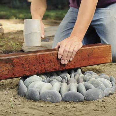 Mark Powers setting and leveling the stones by using a rubber mallet and scrap 4x4 in his pebble mosaic