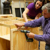 Tom Silva and Amy Paladino install furring strips in order to mount the pegboard on the side of the tool bench