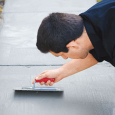 man trowels concrete resurfacer onto a concrete walkway