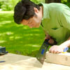 man using pull saw to make king crown for yard game of kubb
