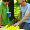 man using handsaw to cut grooves on kubb pieces