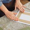 woman secures the photos to the back of mat with paper tape