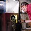 man scraping out built up carbon from furnace