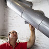 man inspecting flue pipe of furnace