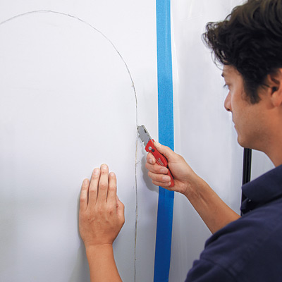 man using utility knife to cut wall for wall niche installation