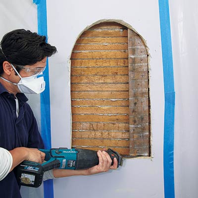 man sawing stud out of wall for wall niche installation