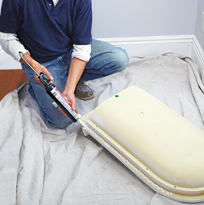 man applying caulk to wall niche for installation