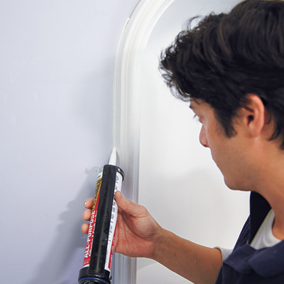 man caulking perimeter of wall niche