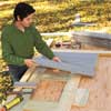 Mark Powers laying out siding before constructing the doors and lids of his trash shed