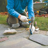 chiseling out the crumbling mortar in a cracked stone walkway