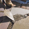 troweling the fresh mortar into joints in a stone walkway