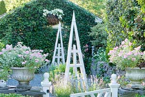pyramid trellis installed in a beautiful yard filled with plants and flowers