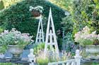 pyramid trellis installed in a beautiful yard filled with plants and flowers