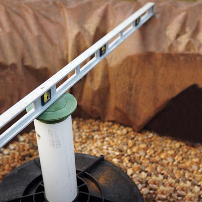 checking with a level to see that the top of the overflow emitter is at ground level