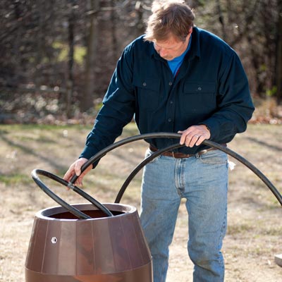 Roger Cook adds tubing to a rain barrel