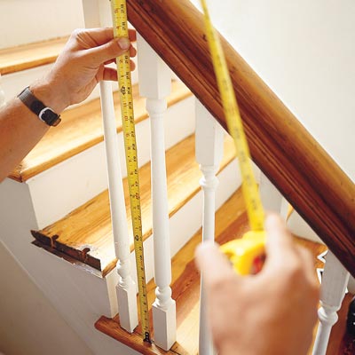 using a tape measure to measure the length of a baluster on a stairway