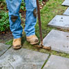 using a half-moon edger to cut around base of each paver in stone stepping path 