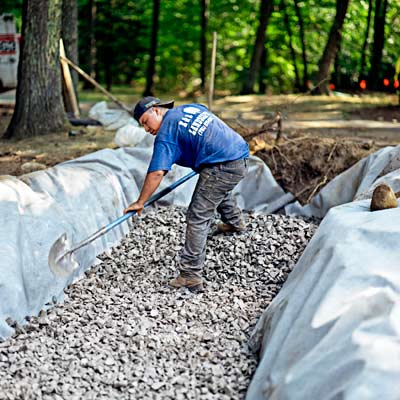 man digging trench for building a fieldstone wall