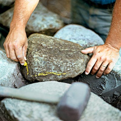 marking stones to cut for building a fieldstone wall