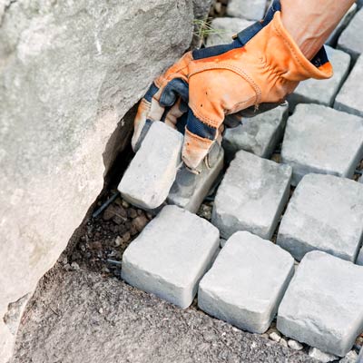 filling gaps with trimmed cobblestones at the edge of a driveway apron