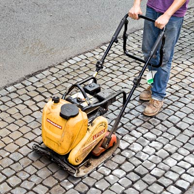 compacting a cobblestone driveway apron with a plate compactor