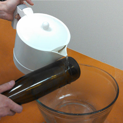 pouring boiled water over a wine bottle to crack it at the score line