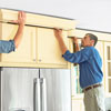 mounting the hardwood frame with crown molding attached to the top of a kitchen cabinet