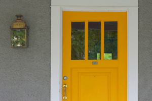 front door with aged light sconce on porch