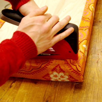 attaching upholstery fabric to the garden bench seat with a staple gun