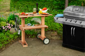 outdoor rolling grill table with grill nearby on patio